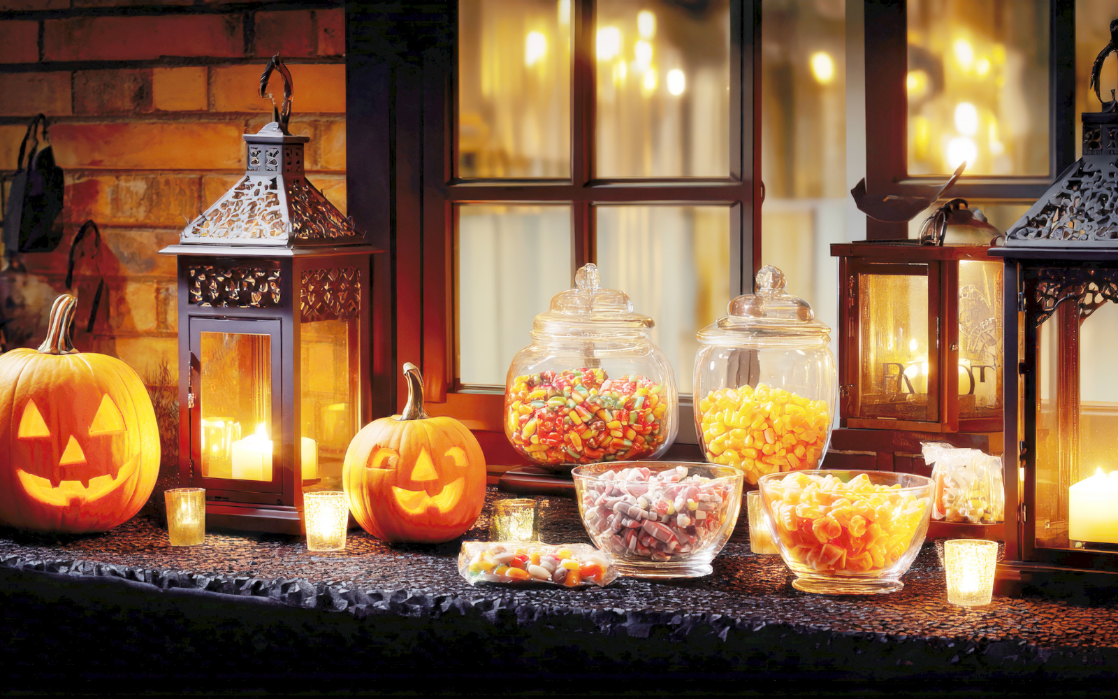Mixed Halloween candy on a table beside carved pumpkins